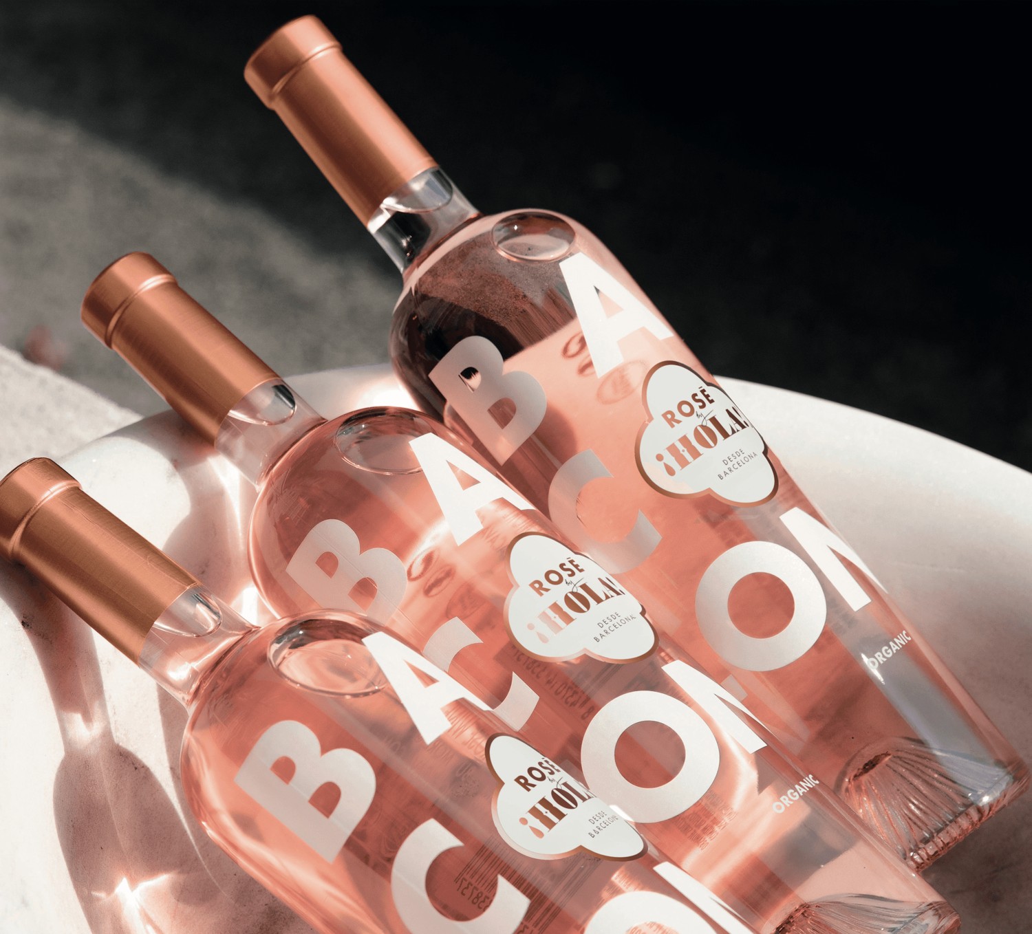 Three chilled Rosé by HOLA bottles together in a sunlit ice bucket