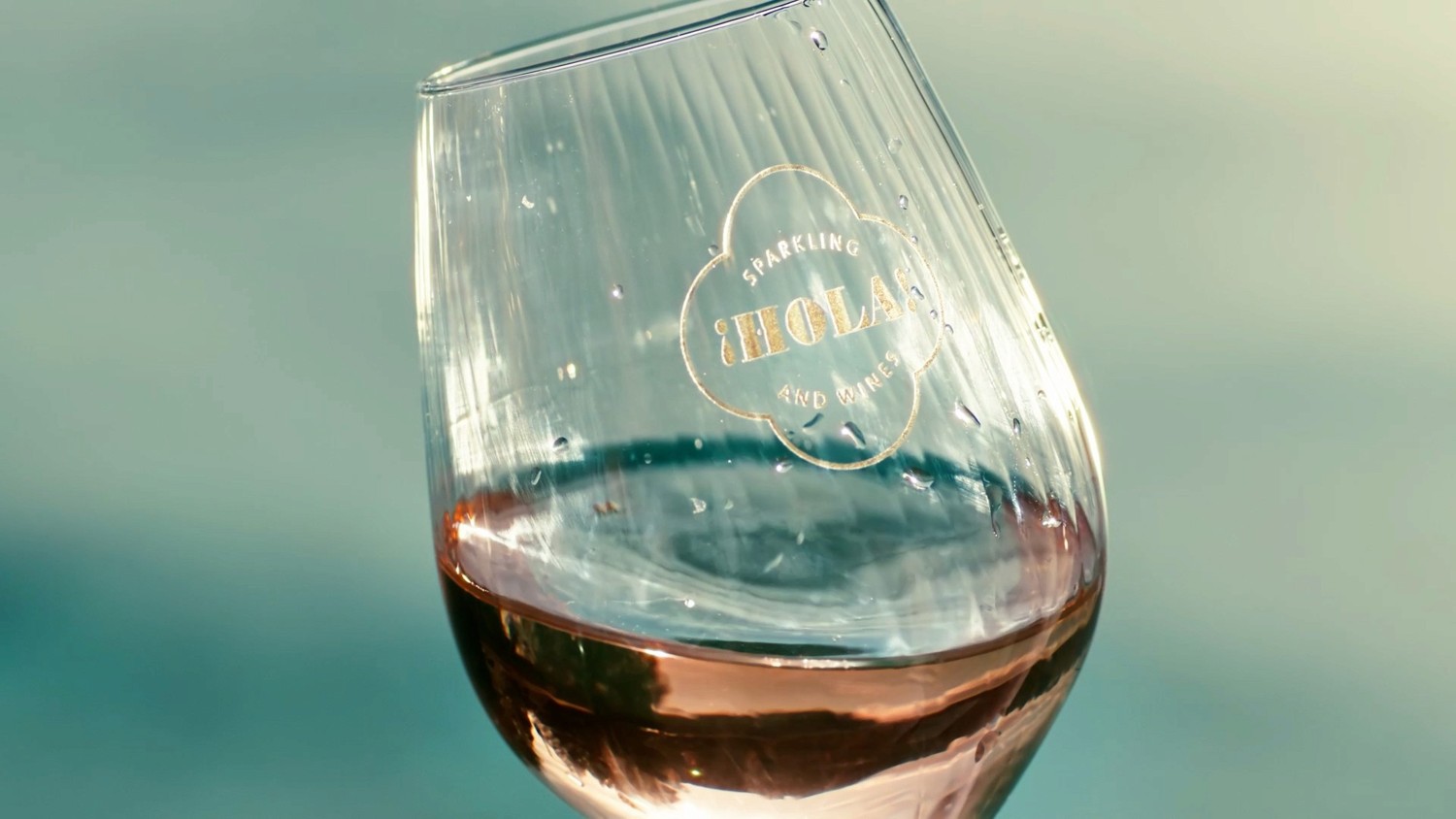 A HOLA wine glass holding pale rosé, catching the sunlight